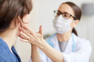 clinician checking patients glands under jawline