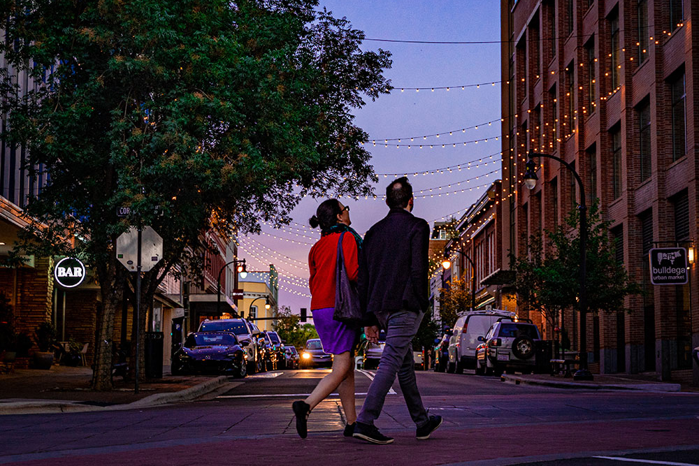 Two people walk in downtown Durham at dusk