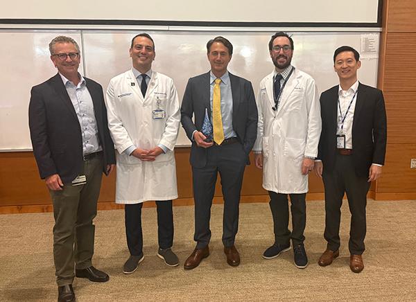 Group of five people posing for a photo in a lecture hall