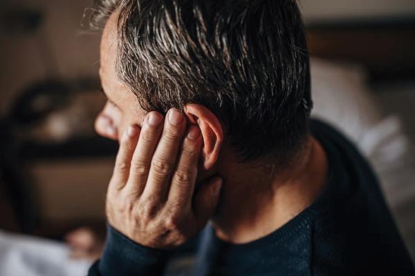 Man touching his left ear