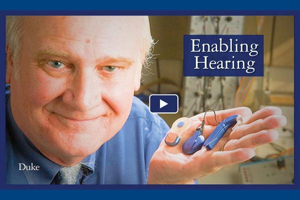 Photo of Blake Wilson holding a hearing aid