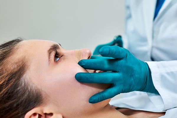 woman getting her nose examined by medical professional 
