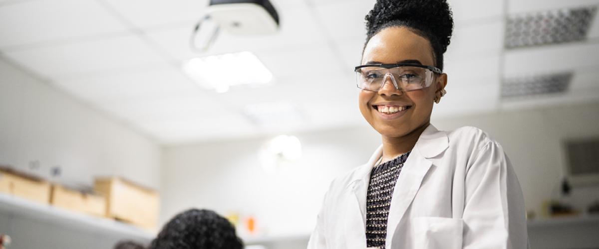 A young black woman in scrubs smiling 