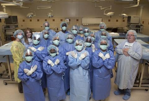 Students from the Durham Nativity School pose in a group photo wearing surgical scrubs, masks, and gloves