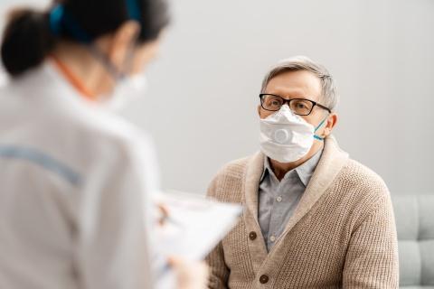 Man in face mask talking to physician