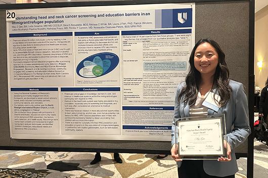 May Gao in front of her poster presentation, holding award