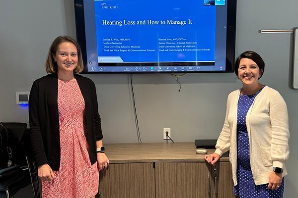 Dr. West and Dr. Hannah Heet in front of their presentation slides