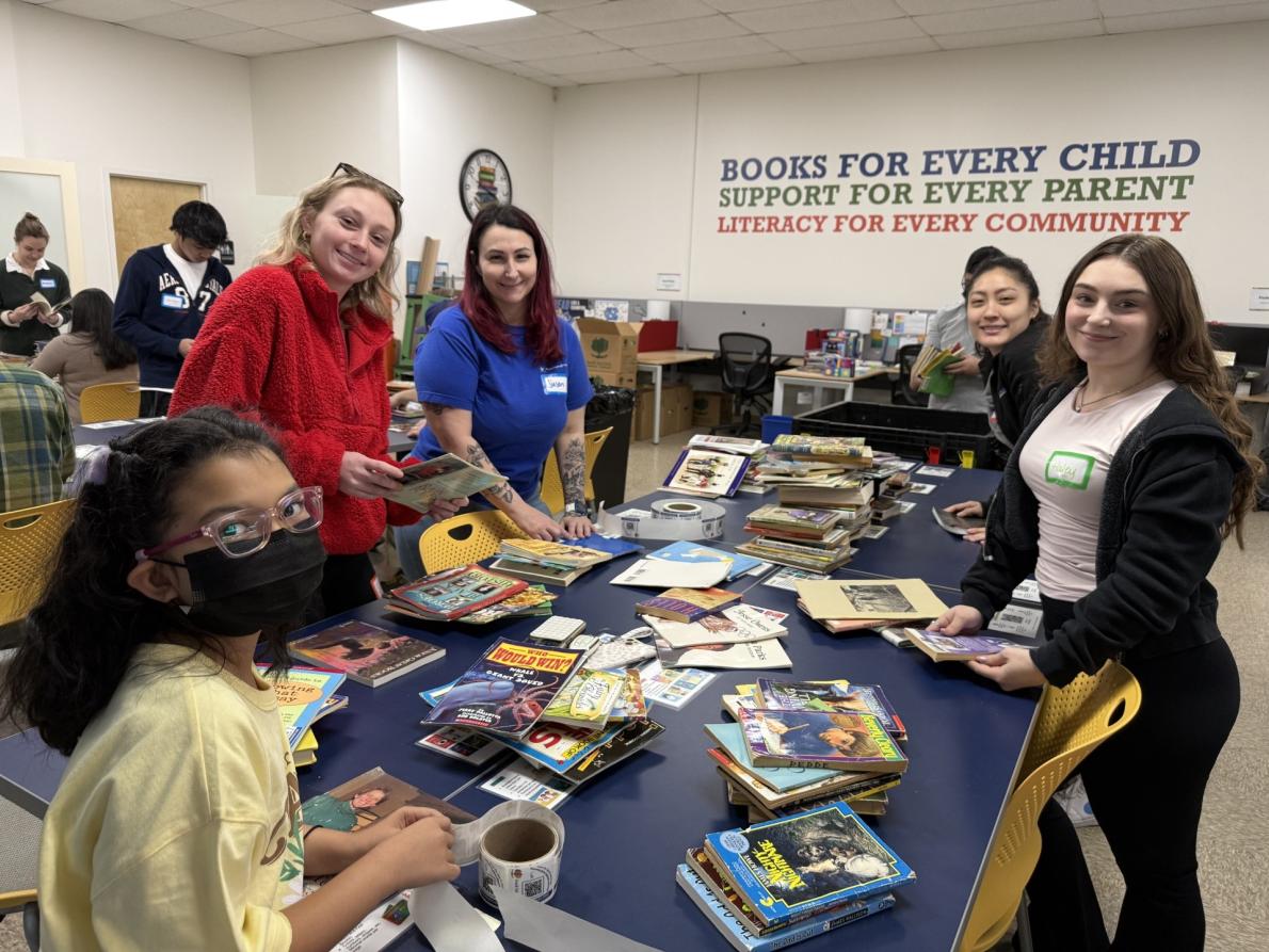 a group of people around a table covered in books