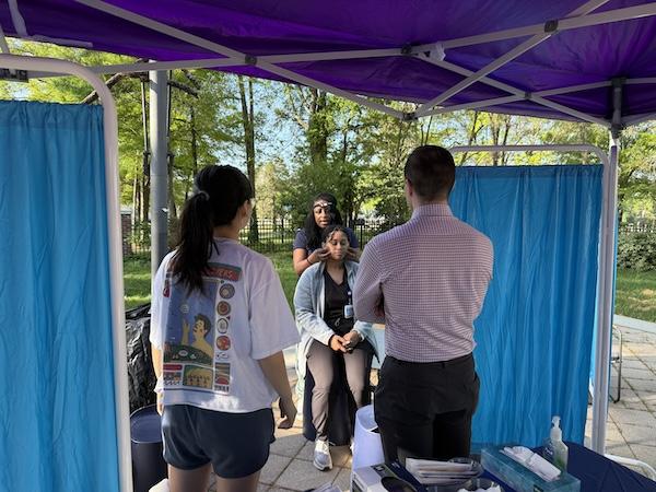 doctor performs a neck cancer screening on a person with two other people watching