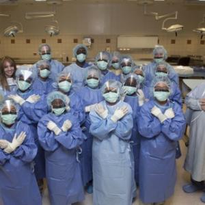 Students from the Durham Nativity School pose in a group photo wearing surgical scrubs, masks, and gloves