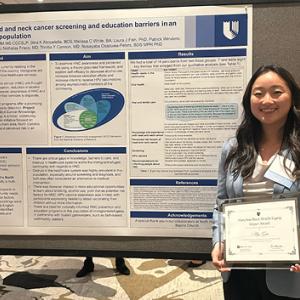 May Gao in front of her poster presentation, holding award 