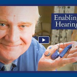 Photo of Blake Wilson holding a hearing aid