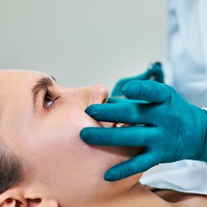 woman getting her nose examined by medical professional 